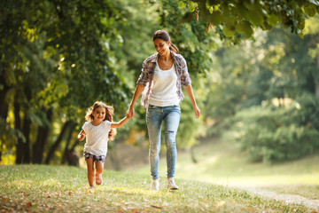mother and daughter playing and running around the park on beautiful morning.
