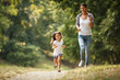 © BalanceFormCreative - Mother and daughter playing and running around the park on beautiful morning.