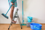 Fototapeta  - Young woman cleaning home with ladder and brush
