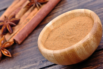 Canvas Print - Cinnamon powder in a bowl with star anise and cinnamon sticks on table