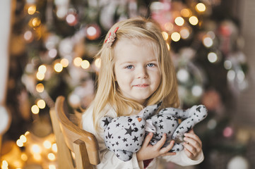 Close-up portrait of blond little girl on the Christmas lights 7