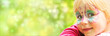 Leinwandbild Motiv glückliches geschminktes Mädchen in einem Freizeitpark blickt in die Kamera