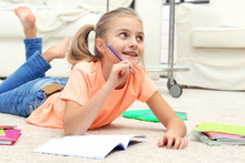 Attractive Little Girl Lying On The Floor And Writing In Copybook