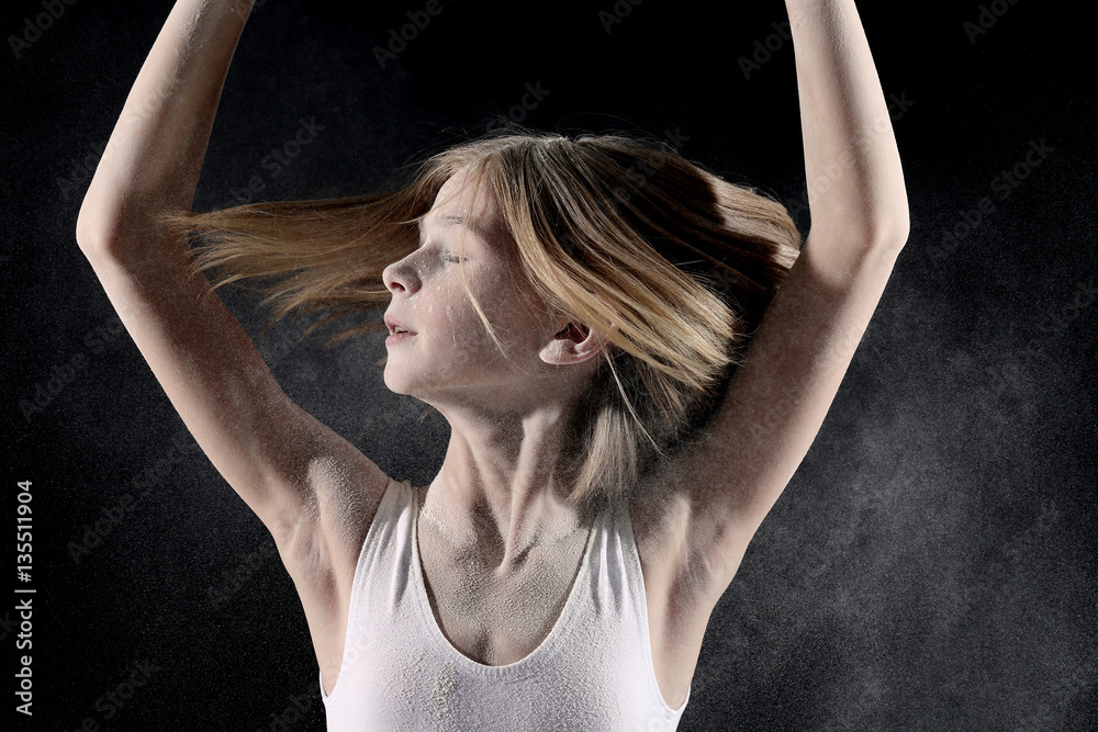 Little cute girl dancing with white powder on black background