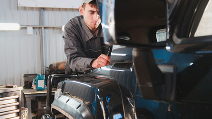 Mechanic looking to hood of the car - automobile service repairing