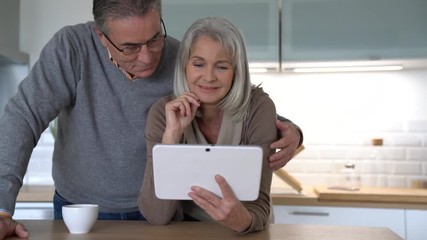 Wall Mural - Senior couple at home using digital tablet