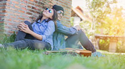 Poster - Hipster man playing guitar for his girlfriend outdoor against br