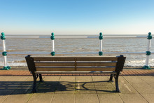 Empty Wooden Bench On A Promenade Overlooking The Sea On A Sunny Day In Winter.