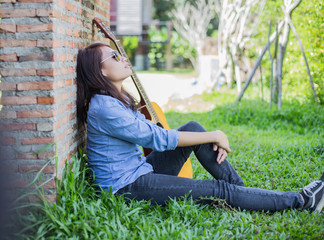 Poster - Hipster man playing guitar for his girlfriend outdoor against br