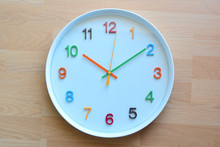 The Colorful Clock On The Wooden Floor Background.