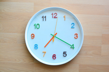 The colorful clock on the wooden floor background.