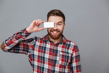 Wall Mural - Cheerful young bearded man holding copyspace business card