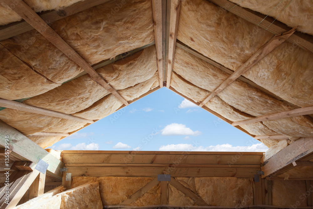 Fibreglass insulation installed in the sloping ceiling of a new frame house. - obrazy, fototapety, plakaty 