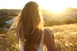 © Julian Walter - Woman looking at sunset with long hair, back to camera