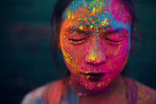 Woman's face covered with colorful paints for Holi Festival