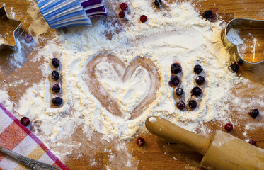 Heart of flour and berries, rolling pin and utensils for baking on wooden background.Happy Valentine's Day. Love and home