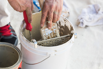 Professional Painter Loading Paint Onto His Brush From A Bucket.