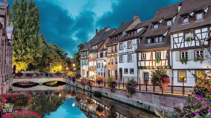 Wall Mural - Colorful traditional french houses on the side of river in the evening in Colmar, France (static image with animated sky and water)
