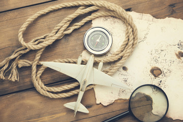 Wall Mural - airplane, old map, compass with magnifier on wooden table