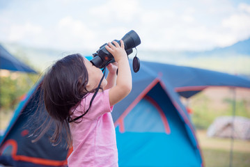 Wall Mural - Little asian girl looking in binocular at camp