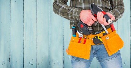 Canvas Print - Mid section of handyman with tool belt and drill machine