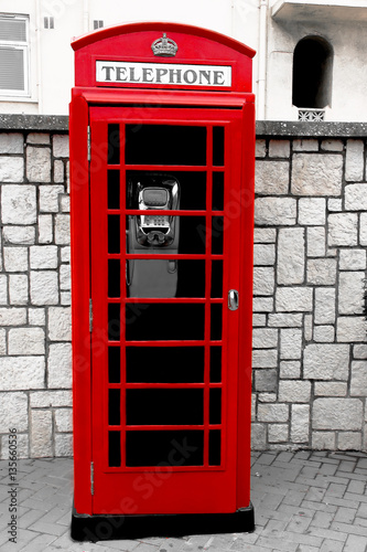 Obraz w ramie Сlassic english telephone booth on a city street. Color in black and white 