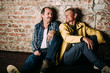 © dashamuller - Two handsome middle aged men, dressed in casual clothing , old friends. Red brick wall background.