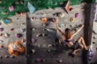Young woman climbing up on practice wall