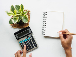 hand holding pancil writing on blank notebook and touch calculator