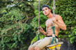 © theartofphoto - Shirtless athlete sitting with the smartphone on the swing. Horizontal outdoors shot.