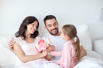 Wall Mural - happy girl giving flowers to mother in bed at home