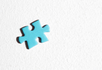 Blue puzzle piece on a white surface.