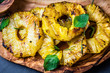 Grilled pineapple slices on olive wooden board. top view