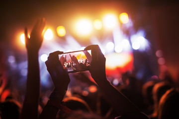 crowd at concert recording atmosphere with their smart phones.