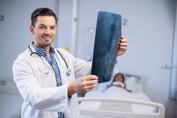 Canvas Print - Portrait of smiling doctor examining x-ray of patient