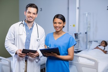 Canvas Print - Portrait of doctor and nurse using digital tablet and clipboard