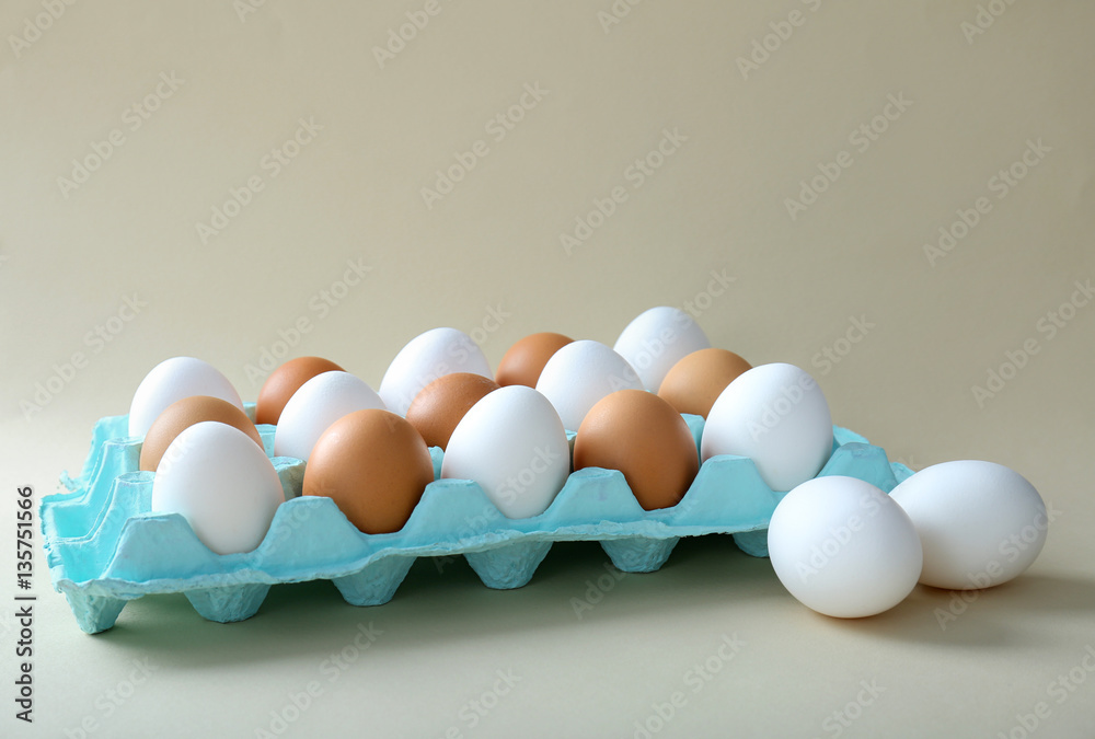 Raw eggs in package on light background
