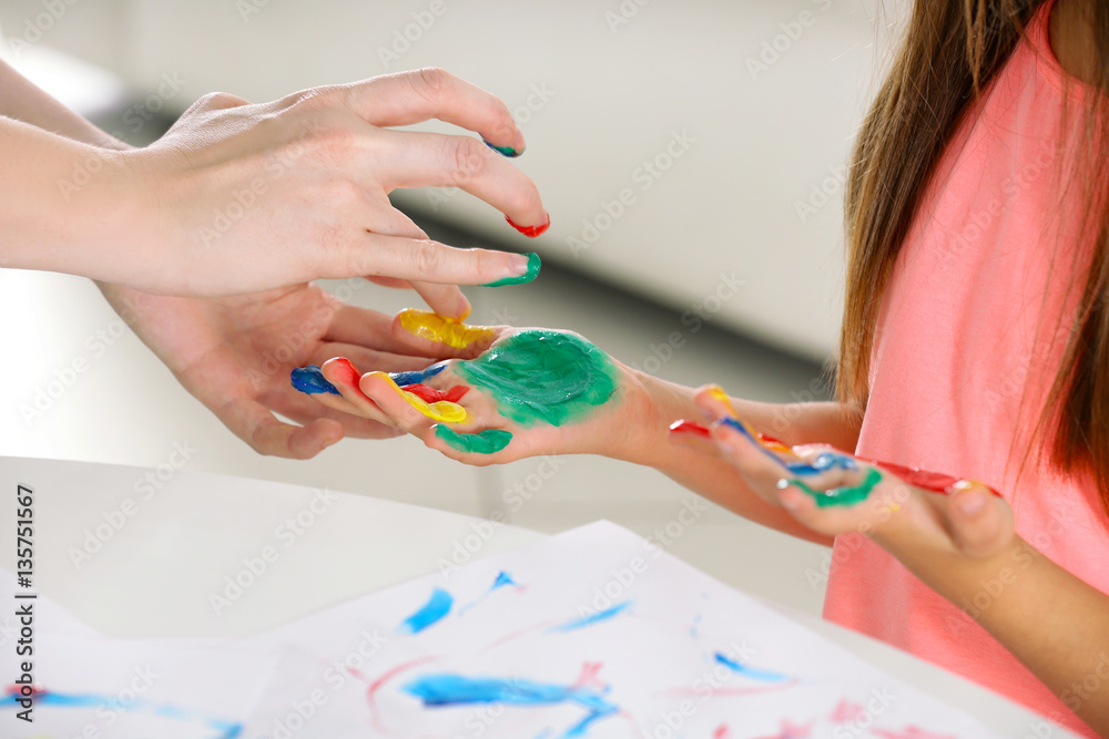 Mother applying paint on daughter's hands