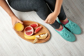 Wall Mural - Woman sitting on the floor with healthy breakfast on wooden tray