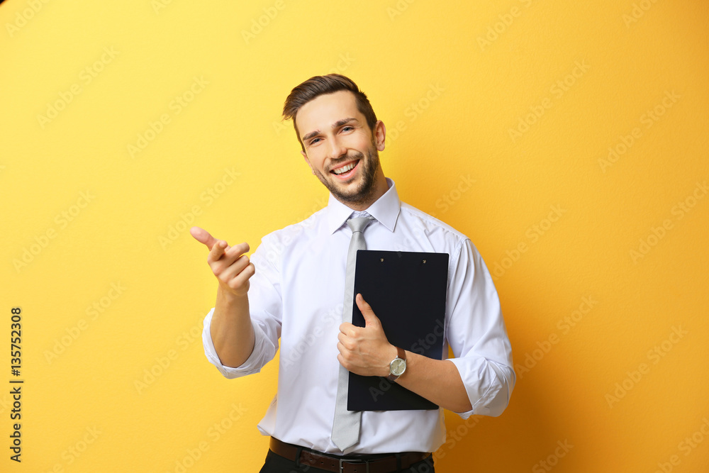 Young man posing with clipboard on yellow background