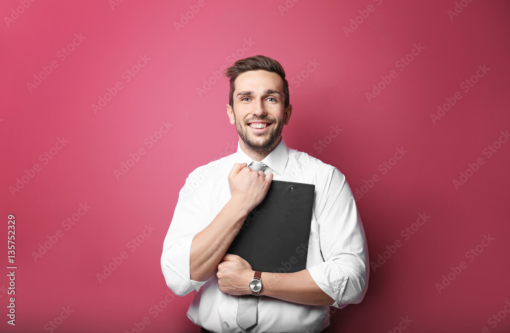 Young man posing with clipboard on pink background