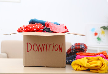 Wall Mural - Donation box with clothing on table