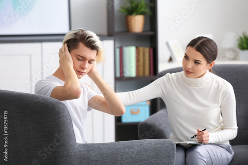 Fotografiet Young female psychologist working with teenager boy in office