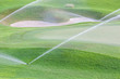 Sprinklers watering system working in green golf course.