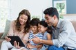 Parents and kids using digital tablet in living room