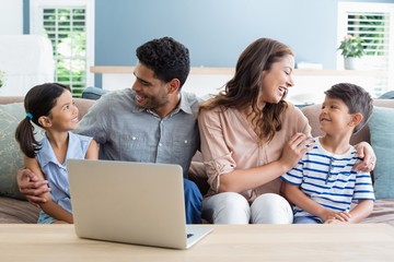 Canvas Print - Happy parents and kids sitting with arm around in living room