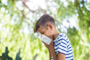 Boy wiping his nose while sneezing