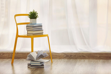 Canvas Print - Pile of books and chair in modern interior