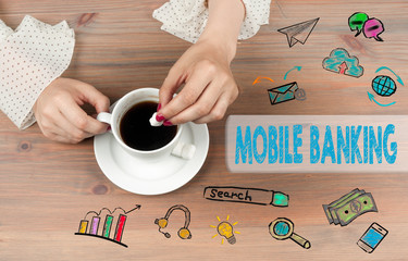 Wall Mural - Mobile banking. Coffee cup top view on wooden table background.
