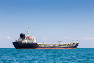 Oil transport ship over seacoaset skyline with clear blue sky